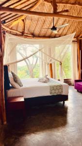 a bedroom with a canopy bed with a window at Yoga bale house in Padangbai +59 photos