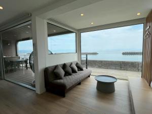 a living room with a couch and a view of the ocean at Thousand Garden Tarumizu in Tarumizu