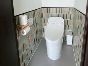 a bathroom with a white toilet in a tiled wall at Thousand Garden Tarumizu in Tarumizu