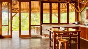 a kitchen with a wooden table and some chairs at Yoga bale house in Padangbai