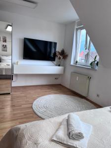 a white bedroom with a flat screen tv on a wall at Fe-Wo im Herzen von Weingarten in Niederdorla