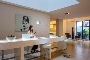 a woman sitting at a desk with a laptop at iH Hotels Milano Watt 13 in Milan