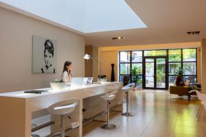 a woman sitting at a desk in a room with a table at iH Hotels Milano Watt 13 in Milan