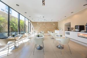 a restaurant with white chairs and tables and windows at iH Hotels Milano Watt 13 in Milan