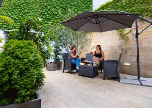 two women sitting in chairs under an umbrella on a patio at iH Hotels Milano Watt 13 in Milan