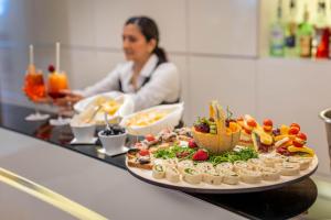 a woman in a kitchen with a tray of food at iH Hotels Milano Watt 13 in Milan
