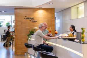 two people sitting at a bar in a restaurant at iH Hotels Milano Watt 13 in Milan