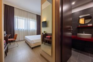 a hotel room with a bed and a bathroom at iH Hotels Milano Watt 13 in Milan