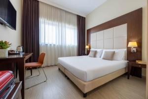 a hotel room with a large bed and a desk at iH Hotels Milano Watt 13 in Milan