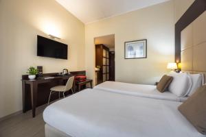a hotel room with two beds and a desk at iH Hotels Milano Watt 13 in Milan