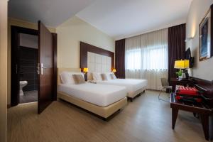 a hotel room with two beds and a bathroom at iH Hotels Milano Watt 13 in Milan