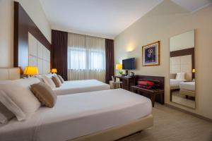 a hotel room with two beds and a living room at iH Hotels Milano Watt 13 in Milan