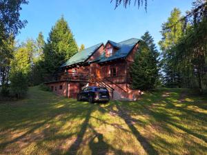 a truck parked in front of a wooden house at Pod Dębem in Giby