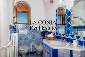 a blue tiled bathroom with a sink and a toilet at blue sea villa in Cannigione