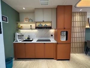 a kitchen with brown cabinets and a refrigerator at Podomoro Medan Lexington Tower - Japandi Modern - New Renovated 2 BR- direct mall access in Medan