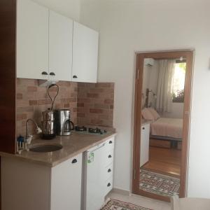 a kitchen with white cabinets and a door to a bedroom at HakimeMilas in Milas