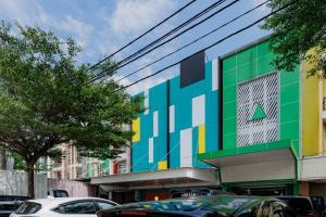 a colorful building with cars parked in front of it at Sans Hotel Harapan Indah in Pulokendal