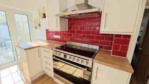una cucina con piano cottura e parete di mattoni rossi di North Cornwall 2-Bed Detached Period Cottage With Parking a Camelford