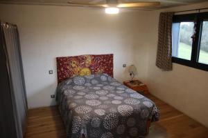 a bedroom with a bed with a patterned comforter at Écolodge Entre Nature & Silence Au Coeur du Quercy in Bétaille