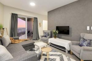 a living room with a couch and chairs and a tv at Sunset On Hill 3 in Bloubergstrand