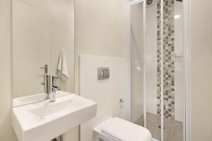 a white bathroom with a sink and a shower at Sunset On Hill 3 in Bloubergstrand +11 photos