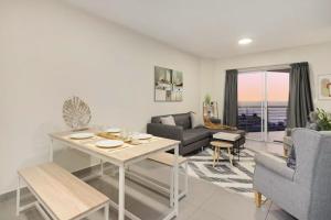 a living room with a table and a couch at Sunset On Hill 3 in Bloubergstrand