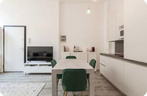 a white kitchen with a table and green chairs at I-Host Apartment - Gallura 11-2 in Milan