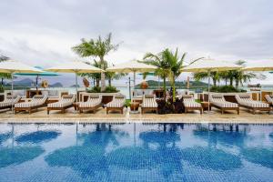 a pool at a resort with chairs and umbrellas at The RIYAZ Lavanya Langkawi in Pantai Cenang