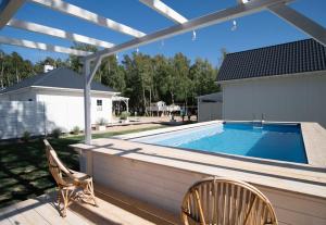 a patio with a swimming pool and two chairs at Off White Domki Darłówko in Darlowko