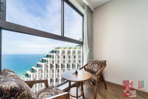 une pièce avec une table et des chaises et une grande fenêtre dans l'établissement Apec Mandala Mui Ne by LHG - Sea View, Infinity Pool, 17m to Bàu Trắng Bình Thuận, à Mui Ne
