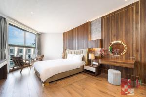 a bedroom with a bed and a table with a chair at Apec Mandala Mui Ne by LHG - Sea View, Infinity Pool, Alacarte, 17m to Bàu Trắng Bình Thuận in Mui Ne
