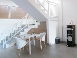 a white dining room with a table and white chairs at Kalyana Guest House in Bandung