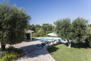 Una piscina con sillas y sombrillas en un patio. en Trulli Stella - Spectacular 3 bed Villa w/Private Pool, en Ceglie Messapica