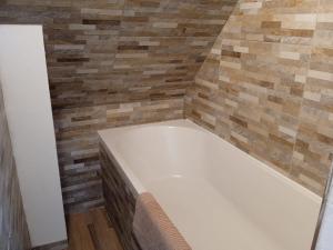 a bath tub in a bathroom with a tile wall at Duplex indépendant dans Longère in La Croix-en-Touraine