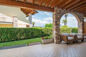 an outdoor patio with an arch and chairs and flowers at Tavaredo House in Polpenazze del Garda