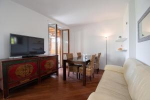 a living room with a tv and a table with chairs at Tavaredo House in Polpenazze del Garda