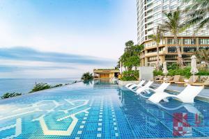 une piscine avec des chaises longues et un bâtiment dans l'établissement Apec Mandala Mui Ne by LHG - Sea View, Infinity Pool, 17m to Bàu Trắng Bình Thuận, à Mui Ne