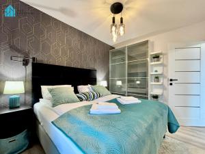 a bedroom with a large bed with two towels on it at Pod Brzozami Apartamenty Gąski in Gąski