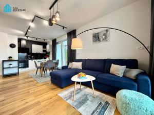 a living room with a blue couch and a table at Pod Brzozami Apartamenty Gąski in Gąski