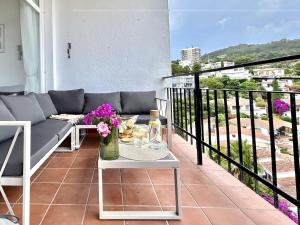 a balcony with a couch and a table with flowers on it at Cala Morisca full AC Sea View Home in Tossa de Mar