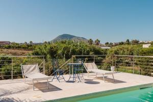 a patio with chairs and a table next to a pool at Villetta Elena in Alcamo