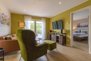 a living room with a green chair and a bedroom at Ferienwohnung Waldblick mit Terrasse und Garten - familienfreundlich in Heringhausen