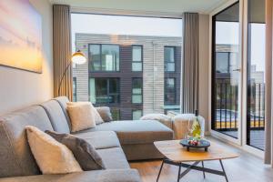 a living room with a couch and a large window at BeltBlick 16 - Moderne Ferienwohnung direkt an der Ostsee mit Meerblick und Sauna! in Fehmarn