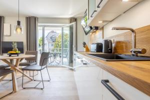 a kitchen with a sink and a table with chairs at Villa Dornkamp 3 - Luxuriöse Ferienwohnung für 4 Personen inklusive Sauna und Balkon in Timmendorfer Strand +5 photos