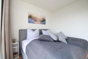 - une chambre avec un lit doté d'oreillers gris et blancs dans l'établissement Suite Relax 3.0 - Die elegante Ferienwohnung mit Dachterrasse, Meerblick und Sauna, à Fehmarn