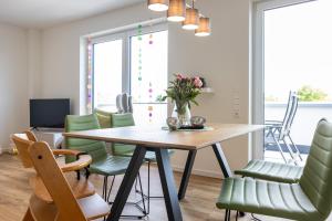 a dining room with a table and green chairs at Penthouse 18 - mit Dachterrasse und Sauna in Dorum