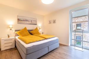 ein Schlafzimmer mit einem Bett mit gelben Laken und einem Fenster in der Unterkunft Kellenhusen Tor 22 - strandnah mit Sauna und Balkon in Kellenhusen
