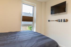 ein Schlafzimmer mit einem Bett, einem Fernseher und einem Fenster in der Unterkunft Kellenhusen Tor 22 - strandnah mit Sauna und Balkon in Kellenhusen