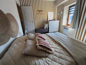 una camera da letto con un letto grande con cuscini sopra di Le cottage de Mag a Cerences 1 altra foto