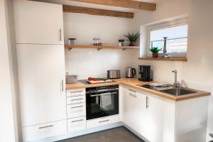a kitchen with white cabinets and a sink at Ferienwohnung Alter Stall - rechte Seite für 3 Personen in Ohne